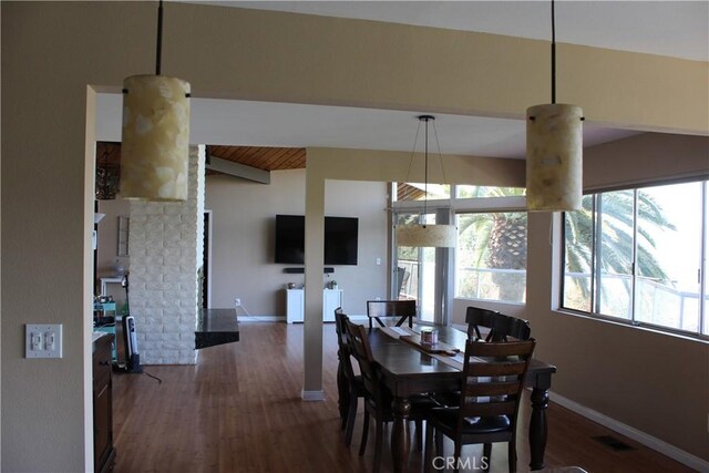 dining room with beamed ceiling, baseboards, visible vents, and wood finished floors