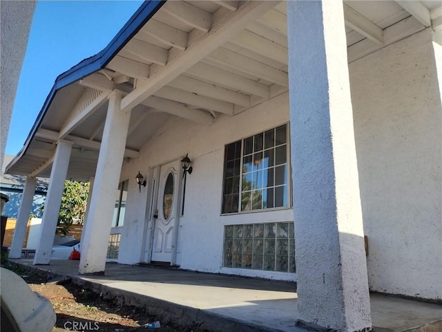 property entrance featuring a porch and stucco siding