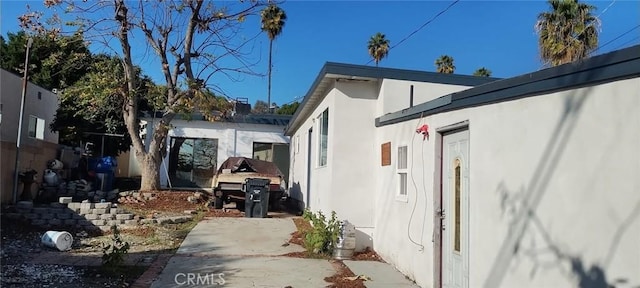 view of side of property featuring stucco siding and fence