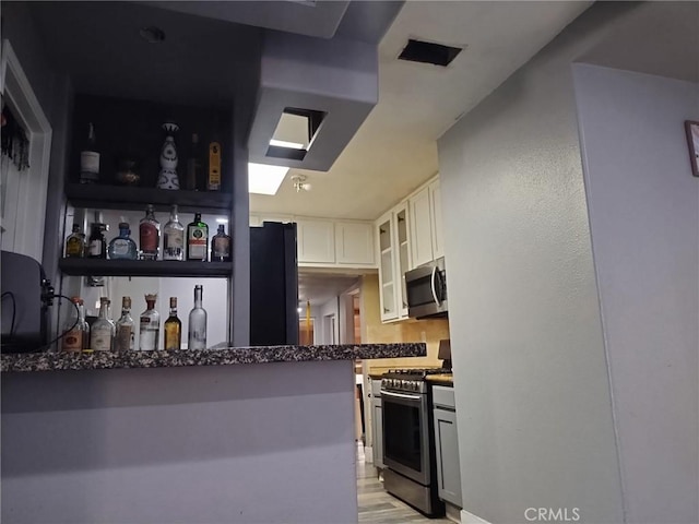 kitchen featuring glass insert cabinets, light wood-style floors, stainless steel appliances, and white cabinetry