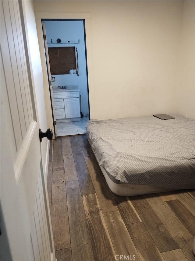bedroom featuring connected bathroom and dark wood-style flooring