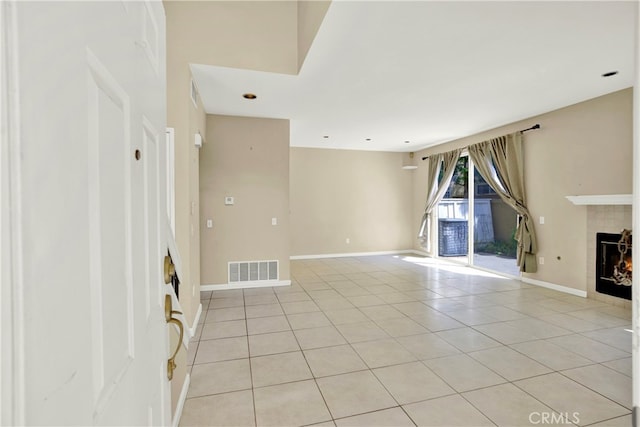 unfurnished living room featuring light tile patterned floors, baseboards, a tile fireplace, and visible vents