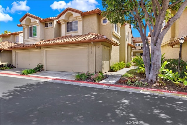 view of front of house featuring an attached garage, a tile roof, and stucco siding