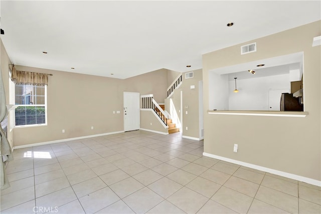 interior space featuring visible vents, baseboards, light tile patterned flooring, and stairway