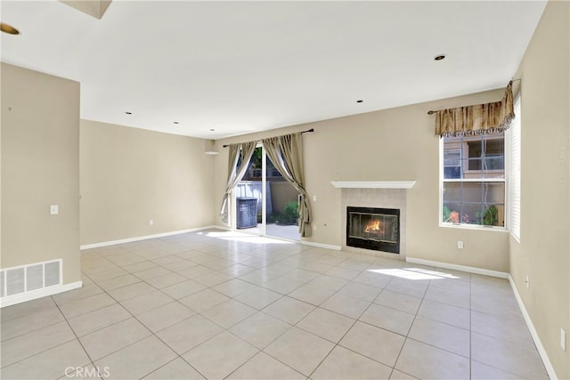 unfurnished living room with visible vents, baseboards, light tile patterned floors, and a tiled fireplace