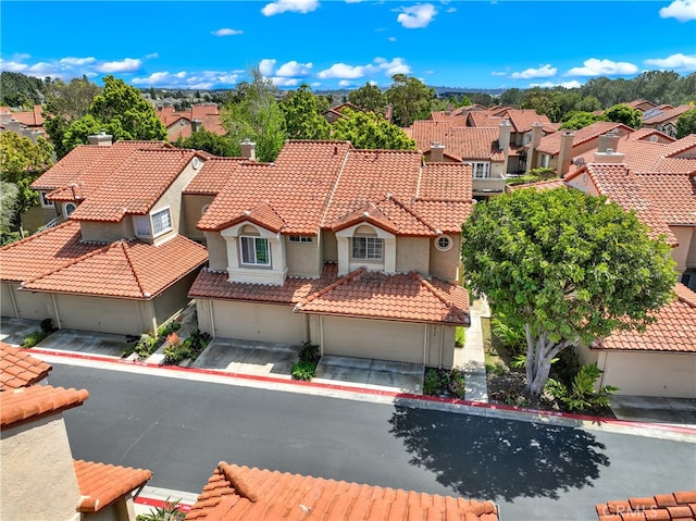 exterior space with a residential view, a tiled roof, an attached garage, and stucco siding