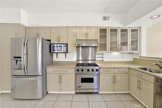 kitchen featuring cream cabinets, a sink, stainless steel appliances, under cabinet range hood, and visible vents
