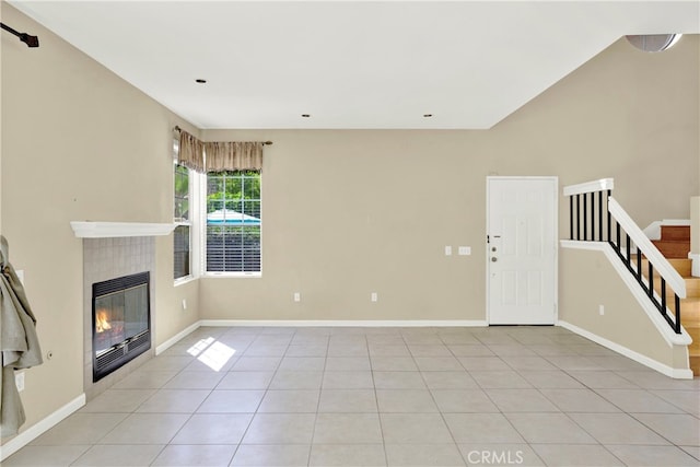 unfurnished living room featuring baseboards, light tile patterned floors, stairway, and a fireplace