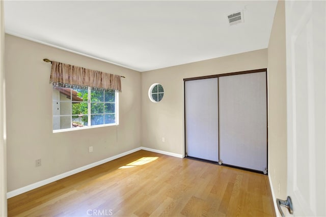 unfurnished bedroom featuring baseboards, visible vents, wood finished floors, and a closet