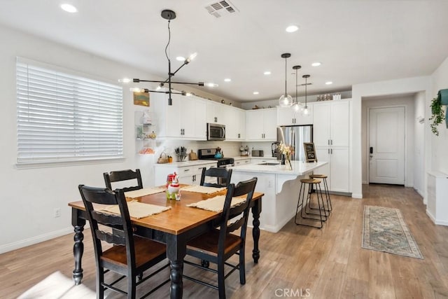 dining space with recessed lighting, visible vents, an inviting chandelier, and light wood-type flooring