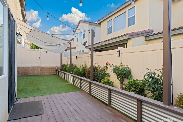wooden deck featuring a fenced backyard and a lawn