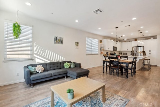 living area with recessed lighting, baseboards, visible vents, and light wood-style floors