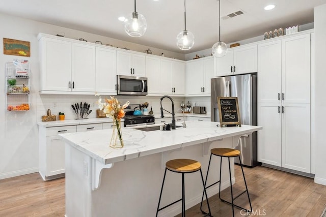 kitchen featuring visible vents, light wood-type flooring, white cabinetry, a sink, and stainless steel appliances