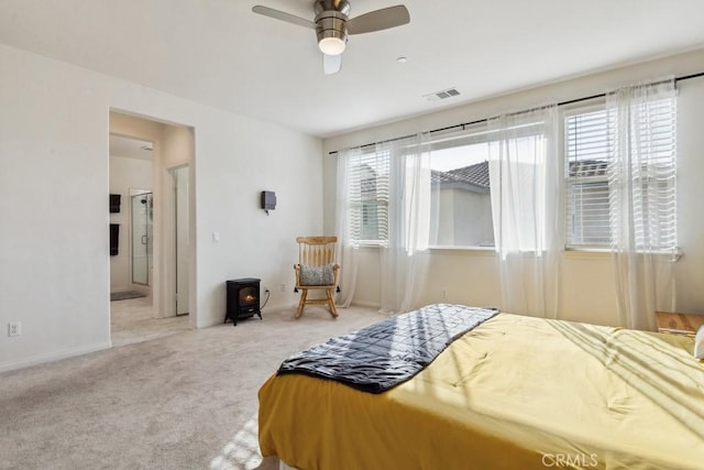 bedroom with carpet floors, visible vents, multiple windows, and a wood stove
