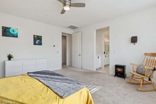 bedroom featuring visible vents, a wood stove, carpet, and a ceiling fan