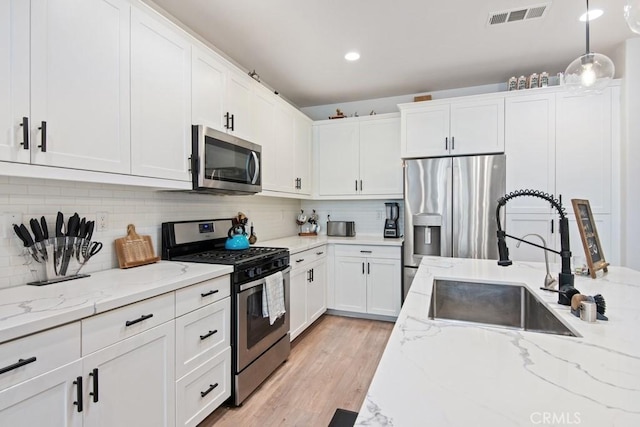kitchen with white cabinets, stainless steel appliances, visible vents, and a sink