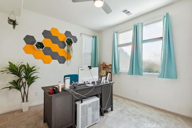 carpeted home office featuring baseboards, a ceiling fan, and visible vents