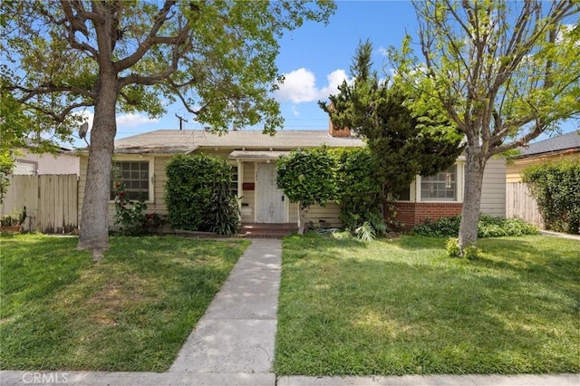 view of front of home with brick siding, fence, and a front yard