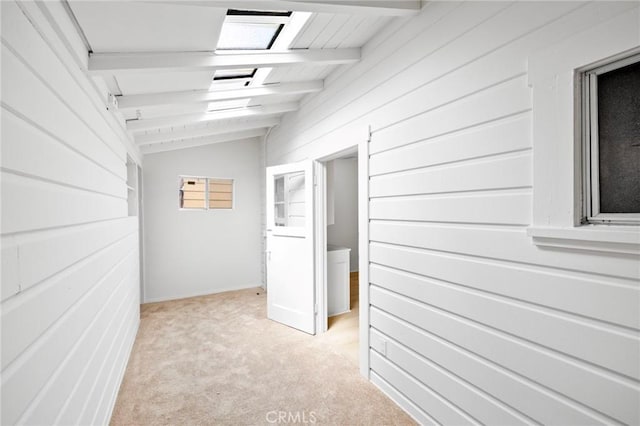 hallway with vaulted ceiling with beams, wooden walls, and light carpet