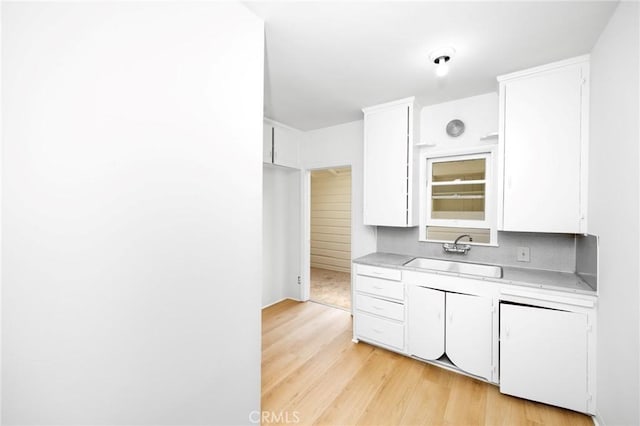 kitchen with a sink, light wood finished floors, and white cabinets