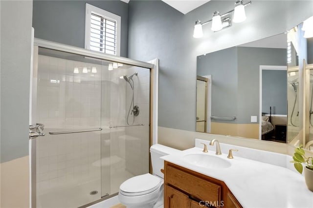 ensuite bathroom with connected bathroom, toilet, a shower stall, and vanity