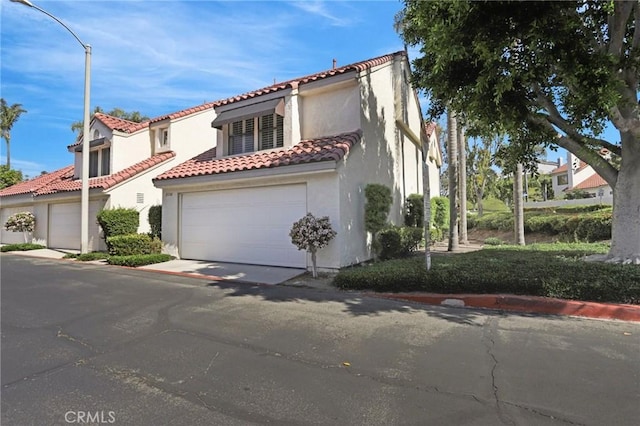 mediterranean / spanish home with stucco siding, concrete driveway, a tile roof, and a garage