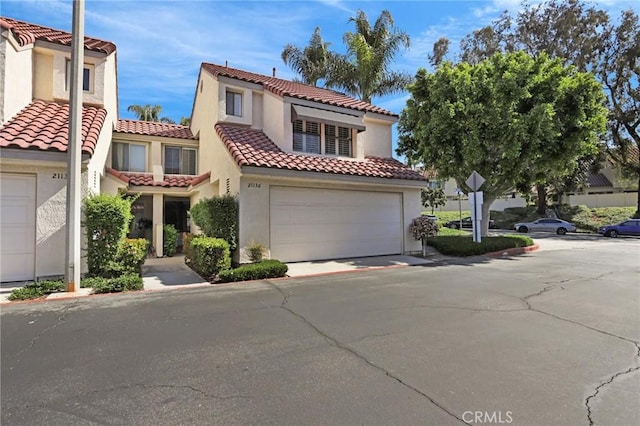 mediterranean / spanish-style home featuring stucco siding, an attached garage, and a tiled roof