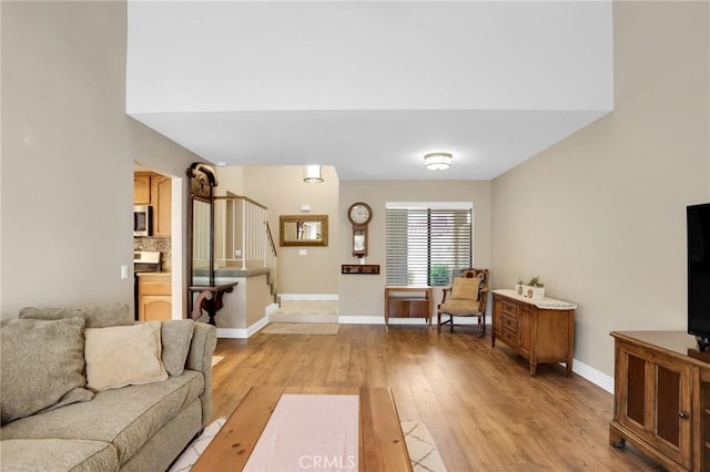 living room featuring stairs, baseboards, and light wood-style floors