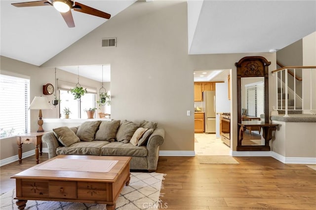 living room featuring baseboards, ceiling fan, light wood-type flooring, and visible vents