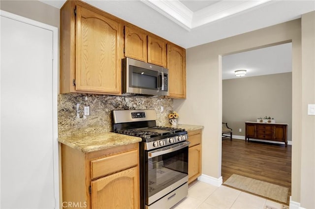 kitchen with decorative backsplash, light countertops, baseboards, ornamental molding, and stainless steel appliances