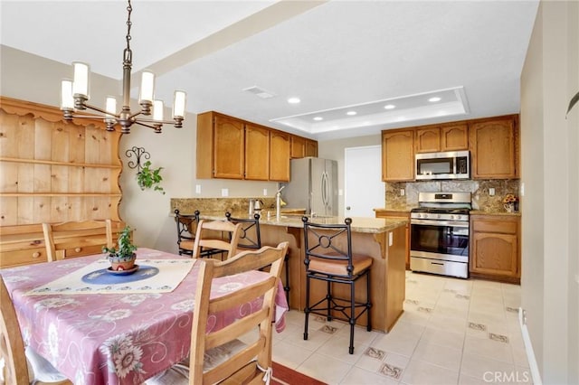 dining room with recessed lighting, a raised ceiling, light tile patterned flooring, and a chandelier