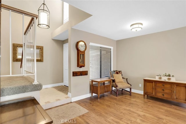 sitting room with baseboards, stairway, and light wood-style floors