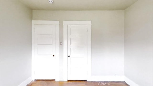 unfurnished bedroom featuring baseboards, a closet, and wood finished floors