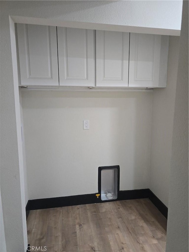 washroom with gas dryer hookup, cabinet space, and wood finished floors