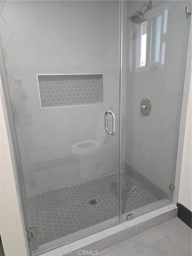 bathroom featuring tile patterned floors, toilet, and a shower stall