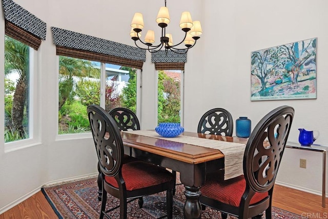 dining area with baseboards, wood finished floors, and a notable chandelier