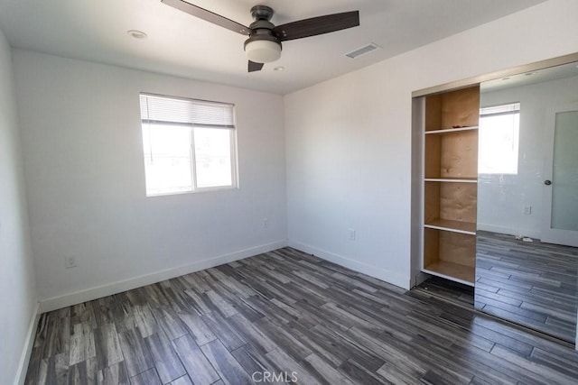 spare room with baseboards, ceiling fan, dark wood-style floors, and visible vents