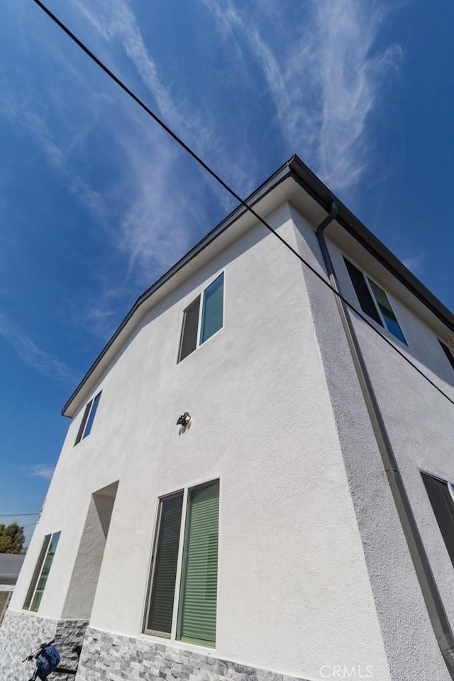 view of side of property featuring stucco siding and stone siding