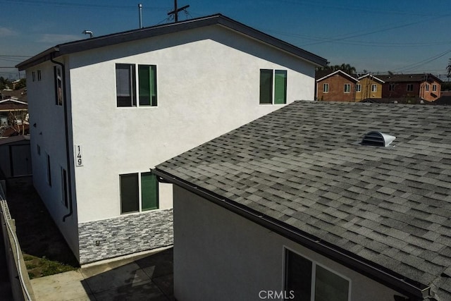 view of home's exterior with a shingled roof and stucco siding