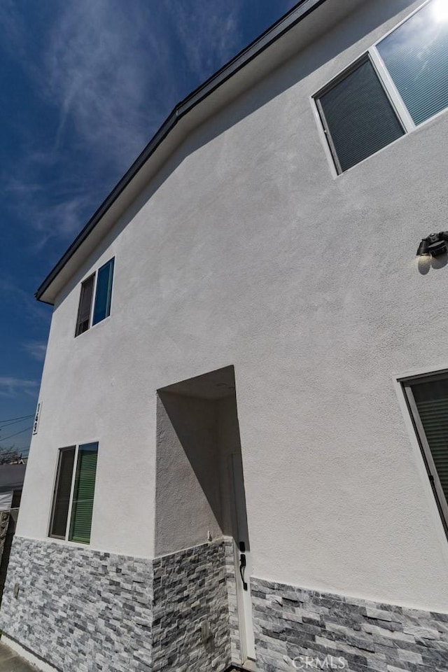 view of side of home featuring stone siding and stucco siding