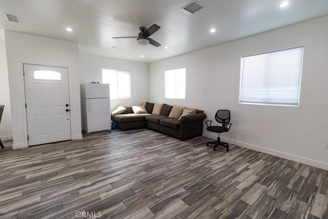 living room with a ceiling fan, visible vents, and wood finished floors
