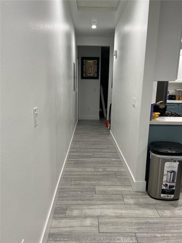 hallway featuring light wood-style floors and baseboards