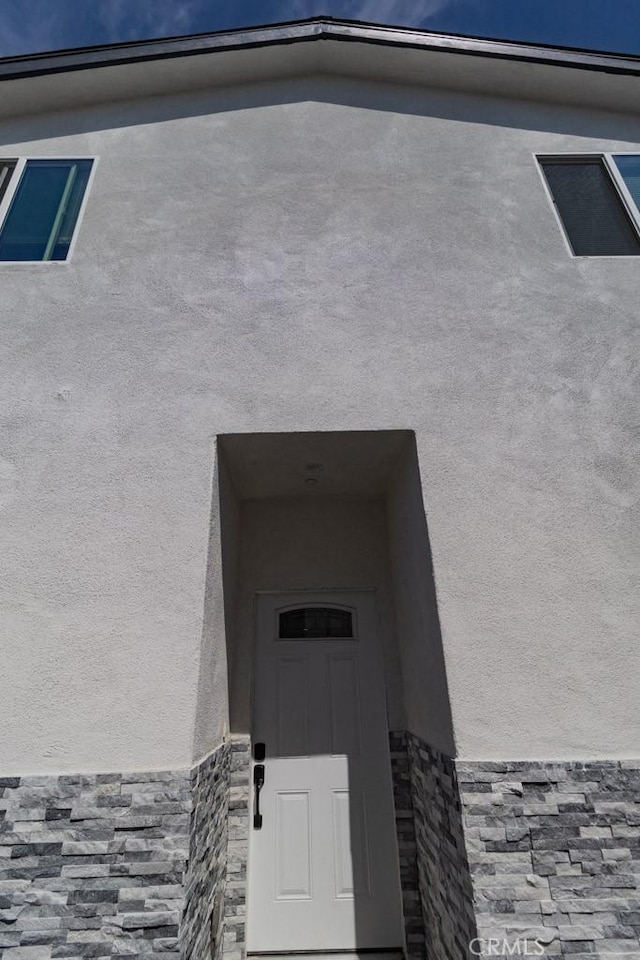 exterior space featuring stone siding and stucco siding