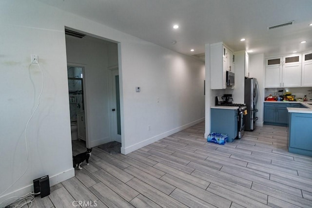 kitchen featuring visible vents, light countertops, white cabinets, light wood finished floors, and stainless steel appliances
