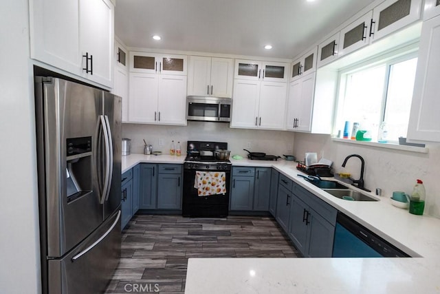 kitchen with a sink, appliances with stainless steel finishes, white cabinetry, and light countertops