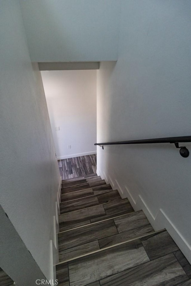 staircase featuring baseboards and wood finished floors