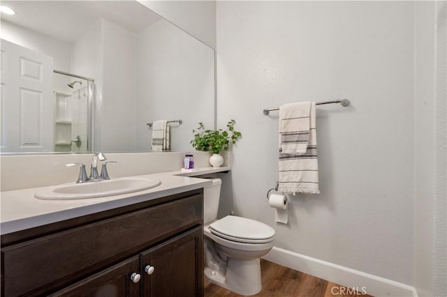 full bath featuring vanity, toilet, baseboards, wood finished floors, and a shower