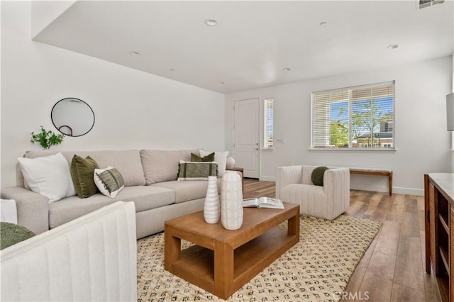 living area with baseboards, visible vents, and wood finished floors