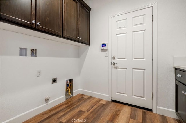 washroom featuring cabinet space, electric dryer hookup, baseboards, and wood finished floors
