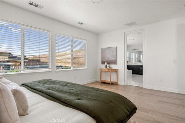 bedroom with baseboards, visible vents, and wood finished floors
